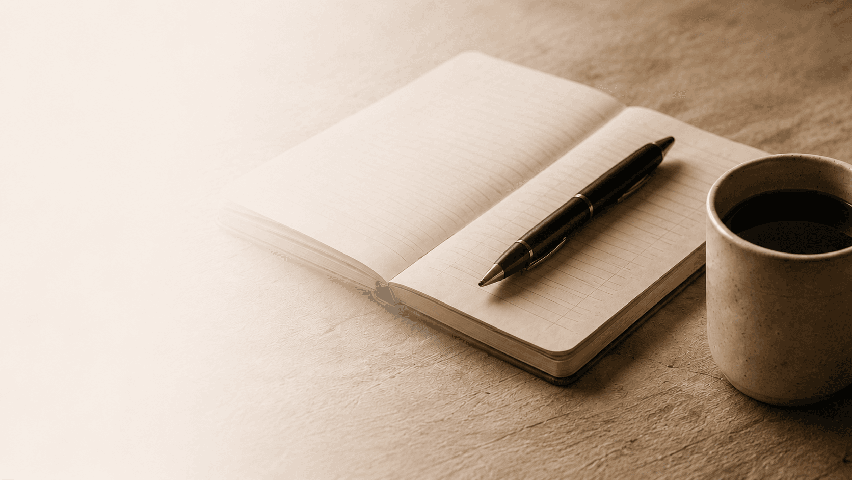 Open notebook, pen, and coffee on a warm desk